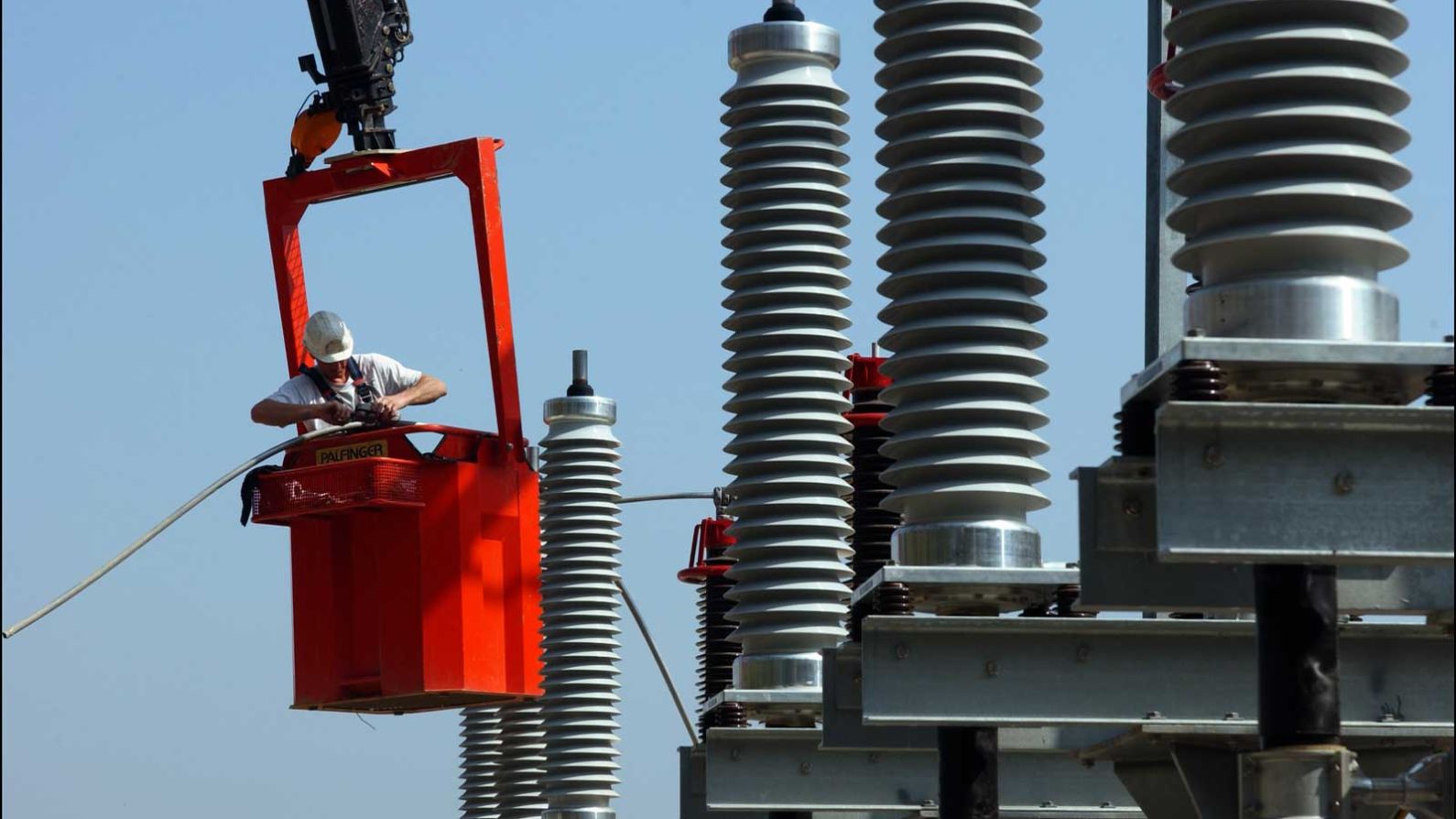 Transformer bushing being lifted by crane rigging during a maintenance intervention