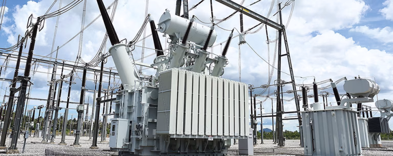 Two large power transformers with cooling radiators in an outdoor utility substation.