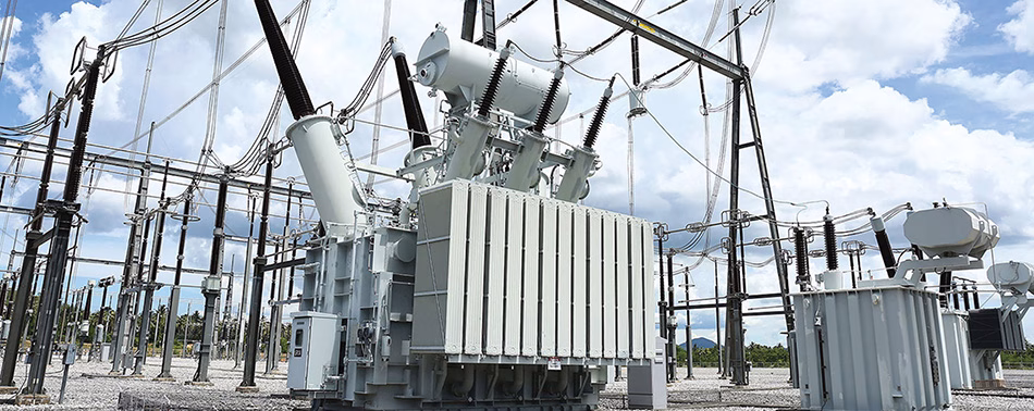 Two large power transformers with cooling radiators in an outdoor utility substation.