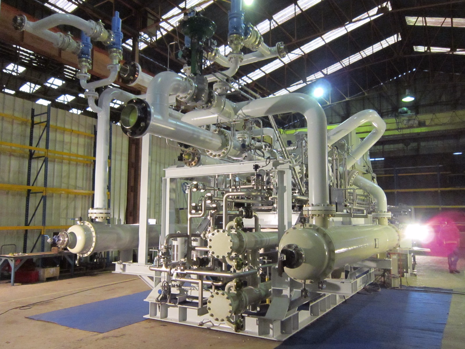 Centrifugal compressor skid with piping inside an industrial workshop.