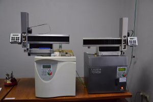 Two gas chromatographs with autosamplers on a laboratory bench.