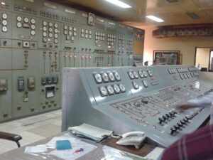 Analogue gauges, switches and paper records in a power plant control room.