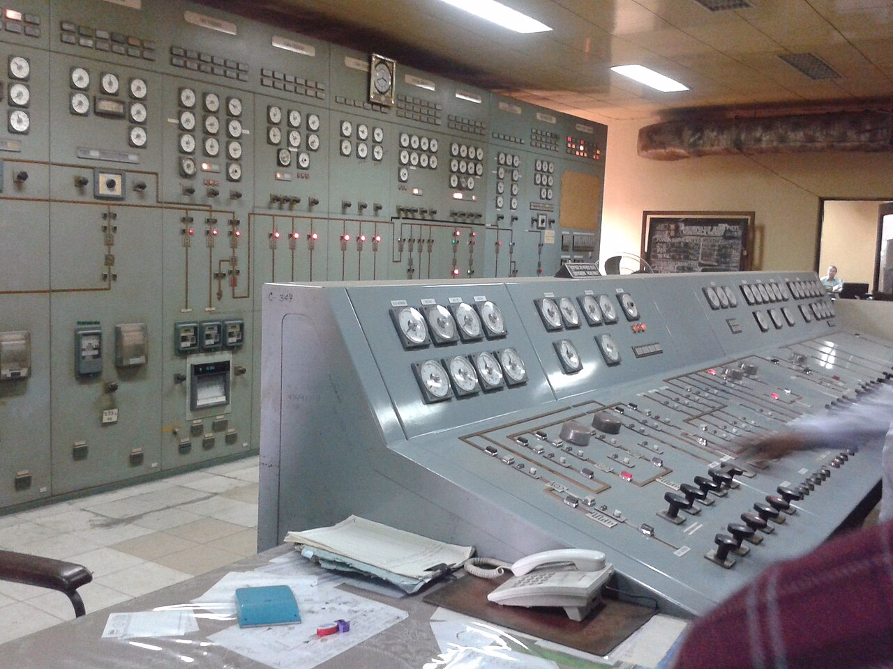 Analogue gauges, switches and paper records in a power plant control room.
