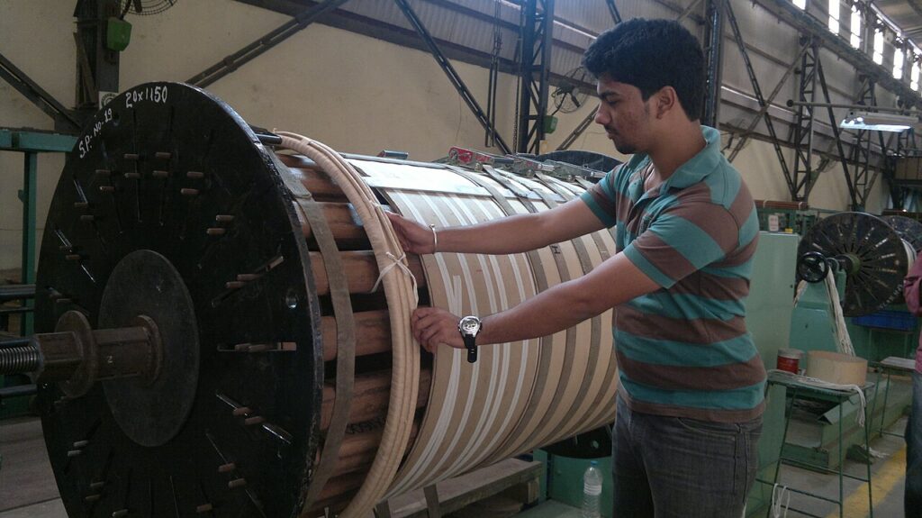 An engineer beside a winding machine used in transformer manufacture