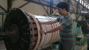 An engineer beside a winding machine used in transformer manufacture.