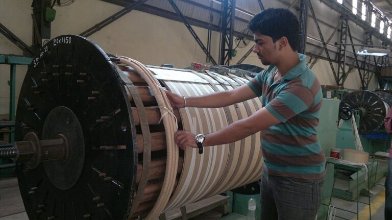 An engineer beside a winding machine used in transformer manufacture.
