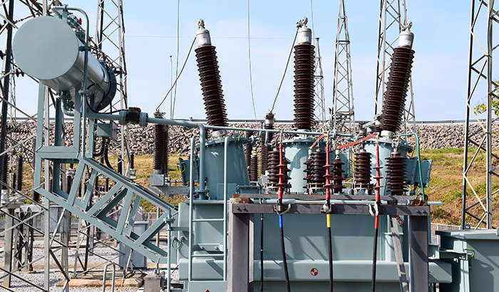 Power transformer with tall bushings and connected equipment in an outdoor substation.