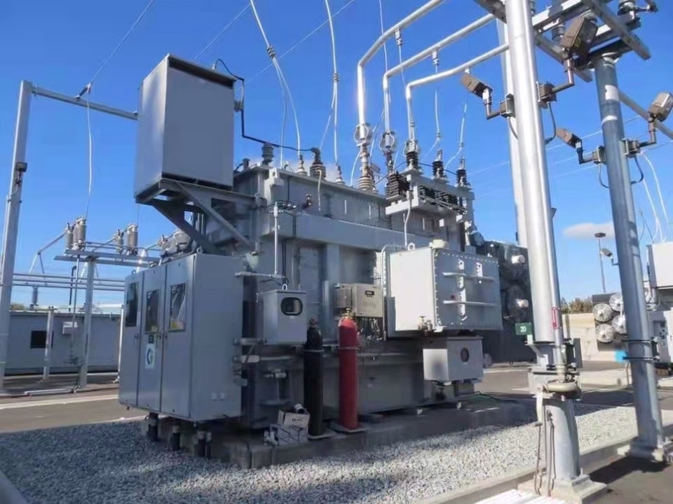 Large oil-filled power transformer with bushings and control cabinets in an outdoor substation.